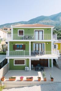 una casa verde con macetas delante de ella en Lakis Residence, en Vlachata