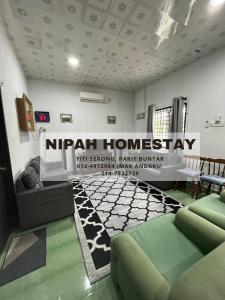 Nipah Homestay Parit Buntar في باريت بونتار: غرفة معيشة مع علامة nirh إقامة منزلية على الحائط
