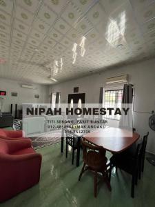 Nipah Homestay Parit Buntar في باريت بونتار: غرفة مع طاولة وكراسي وعلامة على السقف