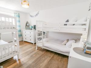 a white bedroom with two bunk beds and a desk at Minerva in Holyhead