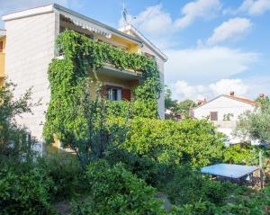 un bâtiment recouvert de lierre avec une table bleue devant lui dans l'établissement Apartment Kova - with pool, à Stari Grad