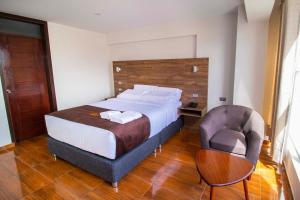 een slaapkamer met een groot bed en een stoel bij Hotel Cumbre Real Airport - Arequipa in Arequipa