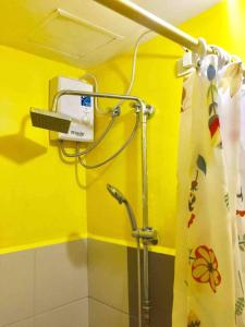 y baño con ducha y pared amarilla. en Budget Grace Residences en Manila