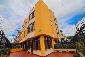 un edificio blanco y amarillo con una valla alrededor en Apto duplex mandarina 2 niveles jardín y parqueo privado!, en Sogamoso