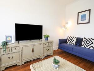 a living room with a blue couch and a flat screen tv at Bryn Tirion - Penrhynside in Conwy