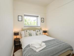 a bedroom with a large white bed with a window at Bryn Tirion - Penrhynside in Conwy