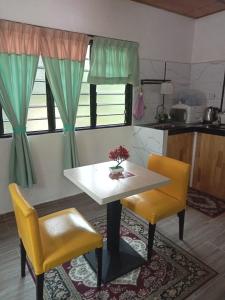 a kitchen with a white table and two yellow chairs at SRI MALAU 