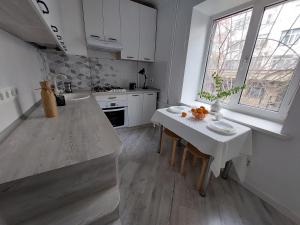 a kitchen with a table and a white counter top at Однушка в белом на Радостовца in Almaty