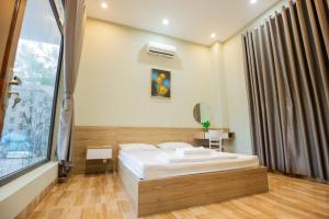 ein Schlafzimmer mit einem Bett und einem großen Fenster in der Unterkunft Palm Villa 27 - 50M To The Sea in Vũng Tàu