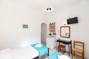 a room with two beds and a desk and a mirror at Peris Rooms in Sifnos
