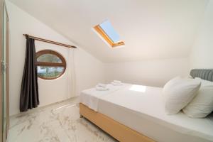 a white bedroom with a bed and a window at Golden Rose Suit pension in Kaş