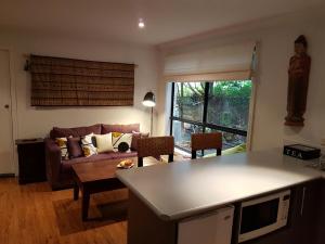 a kitchen and living room with a couch and a table at Dolphin Cottage Garden Studio in Huskisson