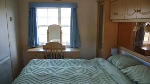 1 dormitorio con cama, escritorio y ventana en Bridge Farm Caravan, en Buxton