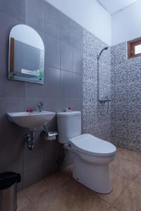 uma casa de banho com um WC, um lavatório e um espelho. em Balkondes Majaksingi Jasamarga em Borobudur