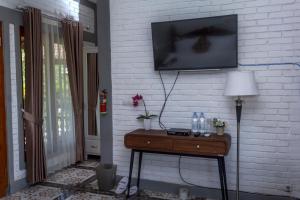 une télévision sur un mur de briques blanches avec une table et une lampe dans l'établissement Balkondes Majaksingi Jasamarga, à Borobudur