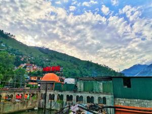 un bâtiment sur une rivière avec une montagne en arrière-plan dans l'établissement Kashmir premium hotel, à Narul