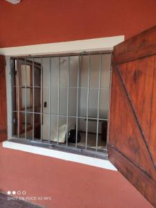un chat derrière une cage dans un mur rouge dans l'établissement Casa Alquiler Cuchilla Alta 2, à Cuchilla Alta