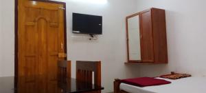a room with a bed and a cabinet and a television at Somatheertham Ayurvedic Resort in Trivandrum