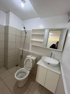 una persona que toma una foto de un baño con aseo y lavabo en KIMEA Staycation in Pasig, en Manila