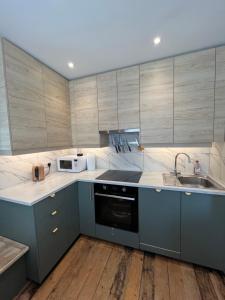a kitchen with gray cabinets and a sink and a microwave at Red Brick House in Yeovil +7 photos