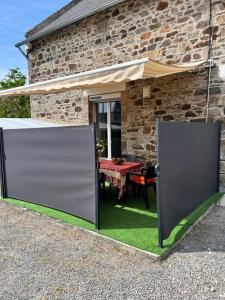 una puerta abierta frente a una casa de piedra con una mesa en ker pincé, en Le Vivier-sur-Mer