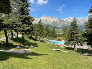 a park with a swimming pool and trees and mountains at Appart 8 personnes piscine sauna pied des pistes in Le Dévoluy