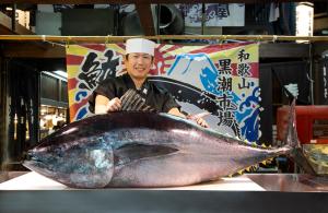 a man in a chefs hat standing next to a large fish at Wakayama Marina City Hotel in Wakayama