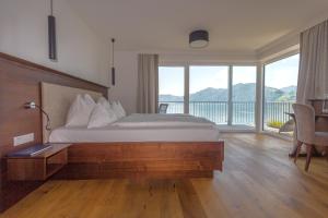 ein Schlafzimmer mit einem großen Bett und einem großen Fenster in der Unterkunft Hotel Stadler am Attersee in Unterach am Attersee