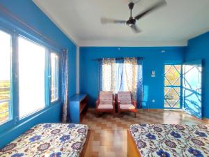 una camera da letto con pareti blu e due letti e finestre di Tranquil Water Guest House a Pokhara