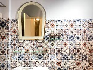 La salle de bains est pourvue d'un mur en carrelage avec un miroir et un lavabo. dans l'établissement BÊ TÔNG RESIDENCES HOMESTAY, à Cần Thơ