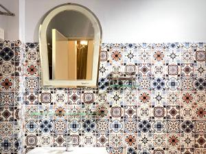 a bathroom with a tile wall with a mirror and a sink at BÊ TÔNG RESIDENCES HOMESTAY in Can Tho