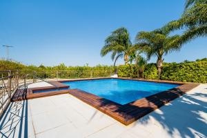 una piscina con terraza y palmeras en El Bancalito Suites and Garden, en Los Montesinos