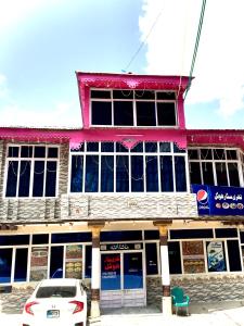 ein rosafarbenes Gebäude mit einem davor geparkt in der Unterkunft Three Star Hotel & Restaurent Malam jabba swat in Malam Jabba