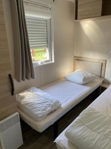 a small bedroom with two beds and a window at Au lac des rêves in Lattes