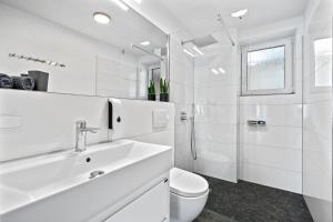 a white bathroom with a sink and a toilet at Villa Dana Bodensee in Friedrichshafen