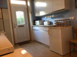 a kitchen with white cabinets and a white refrigerator at 4 Kames Bay in Millport