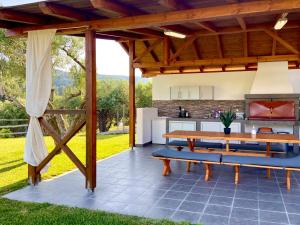 an outdoor kitchen and dining area with a wooden pergola at Panorama Dream Studios B in Vourvourou
