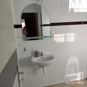 a white bathroom with a sink and a mirror at Apartament pod Lipą in Kłodzko