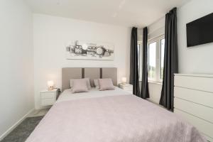 a white bedroom with a large bed with two pink pillows at Kuća za odmor Marita in Privlaka +51 photos