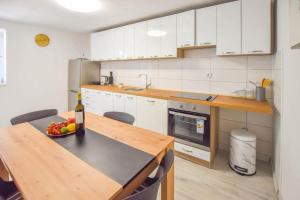 a kitchen with white cabinets and a table with a bowl of fruit at Suite Apartment Toni in Poljana +7 photos