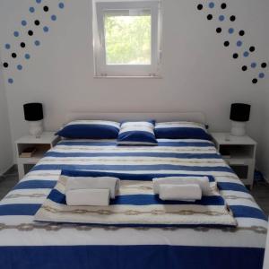 een blauw en wit bed in een kamer met een raam bij Sound of the sea in Vrsi