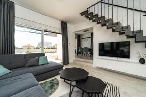 a living room with a gray couch and a tv at Kuća za odmor Marita in Privlaka