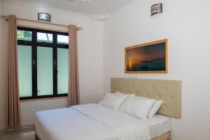 Cama blanca en habitación con ventana en Rushkokaa Beach Villa, en Fulidhoo
