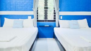 Monkeyland Cham island Homestay في Tân Hiệp: سريرين في غرفة بجدران زرقاء وبيضاء