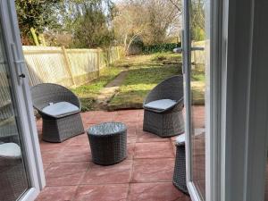 trzy wiklinowe krzesła i kosz na śmieci na patio w obiekcie Peaceful Home in Surbiton, Surrey, Greater London- Free parking w mieście Surbiton