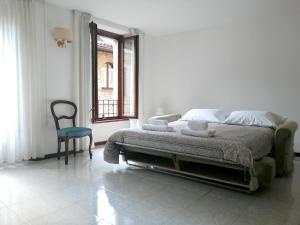 een witte slaapkamer met een bed en een stoel bij Golden Lake in Como