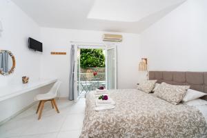 a white bedroom with a bed and a desk and a window at Averto Corfu Apartments in Dassia