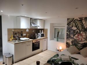 a kitchen with white cabinets and a couch in a room at La Passerelle in Mernel