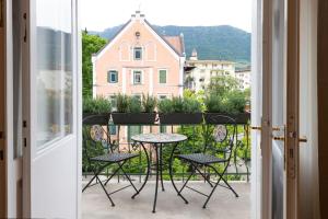 un balcone con tavolo e sedie e un edificio di Meranosuites a Merano Altre 4 foto