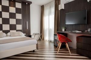 a hotel room with a bed and a desk and a chair at Dan Hotel in Riccione